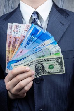 Bir adam elinde ruble ve dolar tutuyor, bir işadamı para elinde tutuyor.
