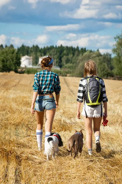 two girls with dogs walking on the field near the forest, the girls travel to Russia