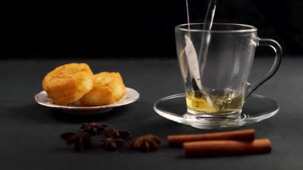 透明なティーポットをガラス皿に引き裂き 黒を背景にアニスとシナモンでお茶を醸造します フルHd — ストック動画