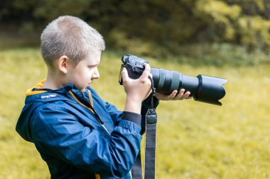 Beyaz bir çocuk DSLR kamerasıyla çekim yapıyor. Doğa ortamı. 