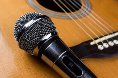 Klasik altı telli gitar boynu ve siyah arka planda gümüş bir mikrofon. Gitar ve aksesuarlar. Yaratıcılık ve gitar çalmak