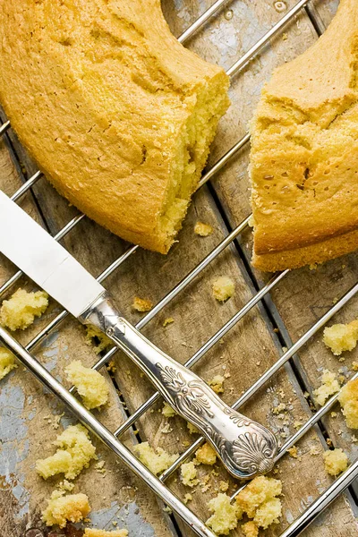 Fırın raf yanında gümüş bıçak üzerinde bütün angel food cake ve rustik ahşap masa kırıntıları yakından