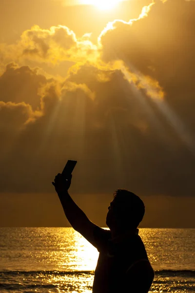 日の出の海に対して Selfie を取る若い男のシルエット — ストック写真