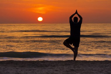 Yoga genç adam poz şafakta denizde meditasyon ağaç
