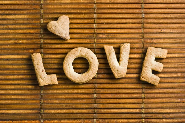 Ev yapımı bisküvi harflerden oluşan aşk kelime ahşap arka plan üzerinde düzenlenmiş