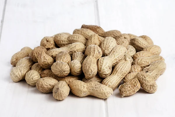 Ahşap beyaz masa üzerinde tüm fıstık demet