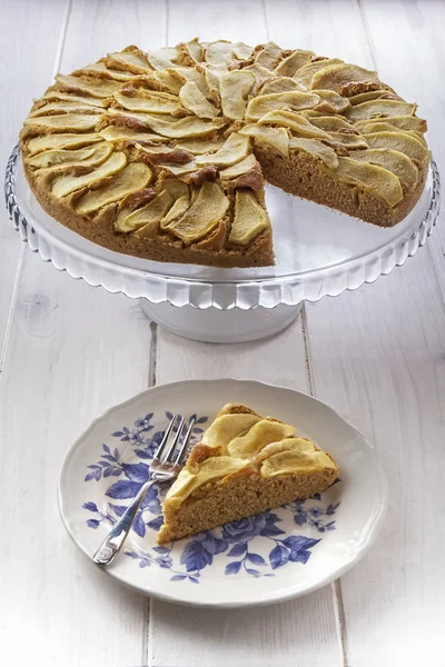 Elmalı turta pasta çatal ile plaka üzerinde ve elmalı turta cam pastayı dilim stand üzerinde beyaz ahşap masa