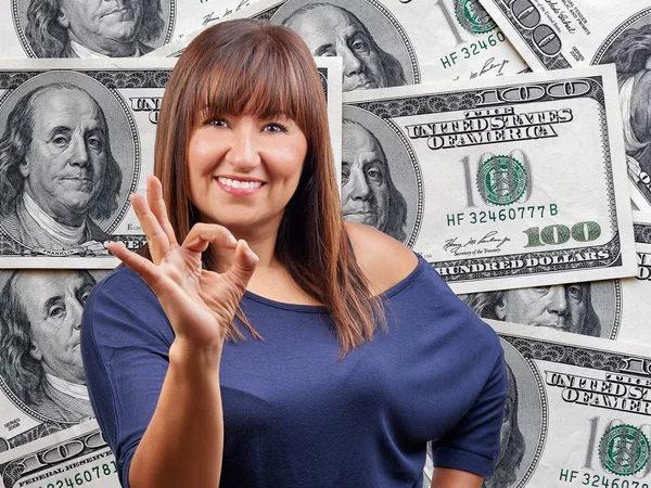 Gelukkig mooi vrouw ok teken gebaar tegen honderd dollar bills heap achtergrond — Stockfoto