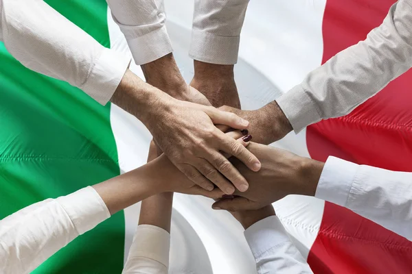 Union or Team Hands multcultural people team over italian flag topview