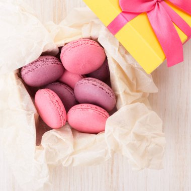 Fransızca macaroons bir kutu içinde. Ahşap bir masa üzerinde sarı bir kutu içinde tatlı kek