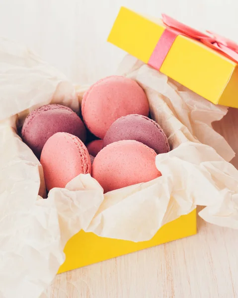 French macaroons in a box. Sweet cakes in a yellow box on a wooden table