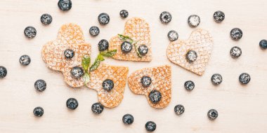 Geleneksel Belçika Waffle taze yaban mersini ve tatlı kiraz Beyaz ahşap zemin üzerinde kalp şeklinde. Düz yatıyordu, en iyi görünüm, kopya alanı.