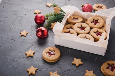 Ahududu veya Çilek reçel gri bir tablo ile klasik Linzer tanımlama. Gingerbread hediye kutusunda. Yıldız ve yuvarlak şekli. Kırmızı yılbaşı ağacı süsleri ve köknar ağacı dalı