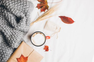 Kırmızı fincan kahve bir yatakta. Sıcak içecek sayfasındaki sıcak rahat gri ekoseli, sonbahar yaprakları ördü. Kraft zarf whith davet. Üstten görünüm veya düz lay, metniniz için kopya alanı
