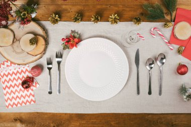 Ahşap masa üzerinde güzel kış dekor ve çatal üstten görünüm Noel yemeği için servis. Tatil arka plan whith tabak, çatal bıçak ve köknar ağacı süsler ve zarfları davet