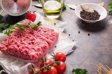 Çiğ taze kıyılmış et, kırmızı kiraz domates, defne yaprağı, tuz ve zeytinyağı, yeşil soğan ve metal tepsi arka plan üzerinde spagetti. Malzemeyi yapıştırmak için. Beyaz Çalarsaat, yemek için kavram zaman