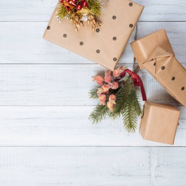 Noel hediyeleri ve kraft kağıt ahşap bir masa, köknar-ağaç dalları ve dekorasyon, üstten görünüm üzerinde hediye kutuları sarılı. Yat, metin için yer Kopyala.