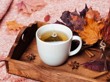 Ev ofis masaüstü ile bir dizüstü bilgisayar, sıcak sıcak pembe kareli, fincan çay tepsisi ve sonbaharda akçaağaç sarı ve kırmızı üzerinde bırakır. Ahşap beyaz masa, düz yatıyordu. Kış ve sonbahar arka plan, üstten görünüm