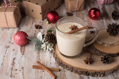 Geleneksel Noel içki yumurta likörü tarçın, Anason yıldız ve ahşap masa üzerinde bir cam kupa rendelenmiş küçük Hindistan cevizi. Gingerbreads, hediye kutuları ve köknar ağacı süsle