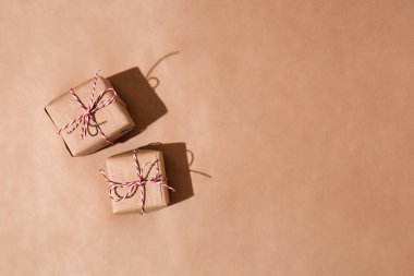 Bir geri dönüşümlü Kraft kağıt sarılmış hediye kutuları, kahverengi bir arka plan üzerinde kırmızı ve beyaz ip. Herhangi bir tatil, yılbaşı, Sevgililer günü veya Doğum günü için modern presents