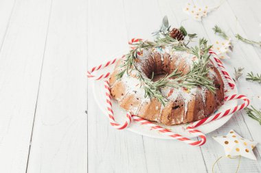 Beyaz ahşap bir masa üzerinde geleneksel Noel meyveli kek. Festival süsleri, baston şekerler ile ev yapımı puding