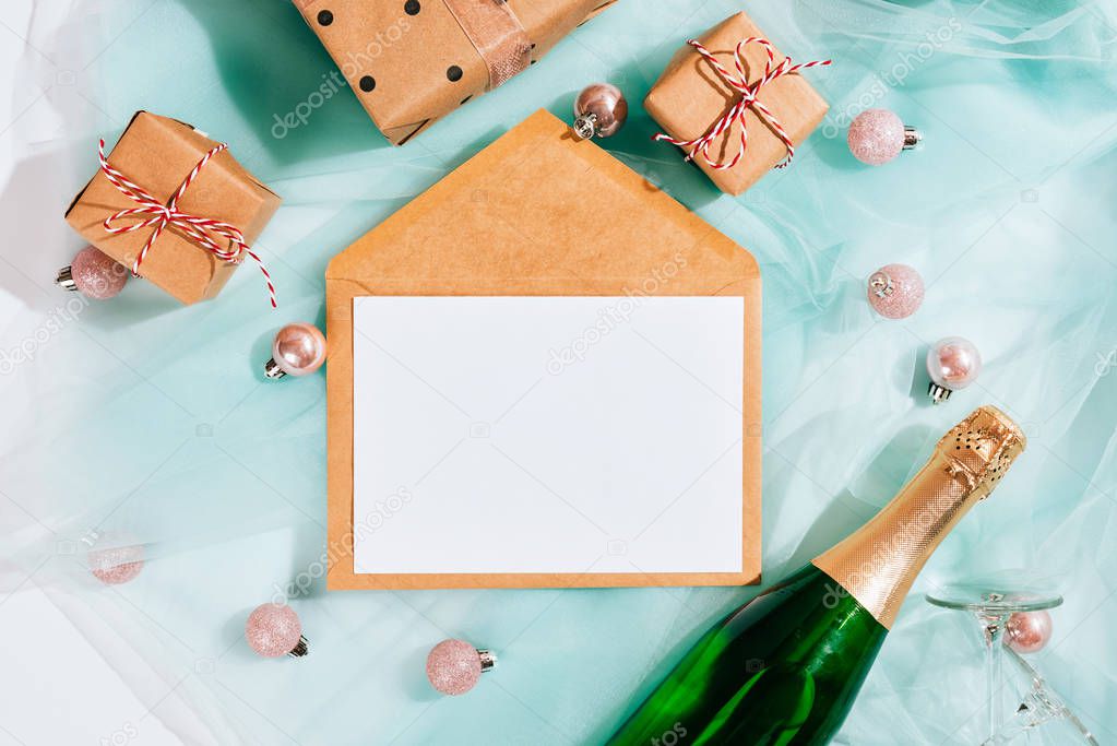 Bottle of champagne and kraft brown envelope on turquoise fabric cloth texture. White background, copy space for your text