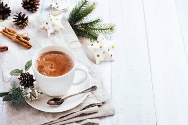 Sıcak çikolata tarçın ile beyaz ahşap masanın üzerine yapışır. Bir peçete, Noel ağacı altın yıldız süslemeleri, dalları ve koniler kış kakao içki