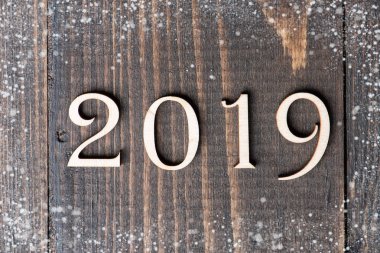 Ahşap basamak numara 2019 üzerinde ahşap arka plan ile kar şekillendirme oyulmuş. Yeni yıl sembolü, üstten görünüm