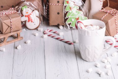 Fincan kakao ya da çikolata ahşap Noel arka plan üzerinde. Kış sıcak çikolata meşrubatının Marshmallow, kardan adam ve bir çam ağacı kurabiye, baston şekerler