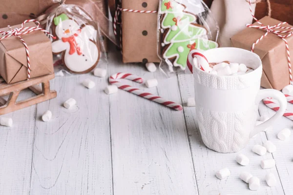Fincan kakao ya da çikolata ahşap Noel arka plan üzerinde. Kış sıcak çikolata meşrubatının Marshmallow, kardan adam ve bir çam ağacı kurabiye, baston şekerler