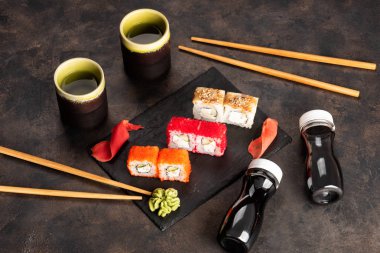 Suşi rulo ve sashimi siyah bir taş plaka.