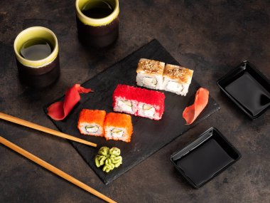 Suşi rulo ve sashimi siyah bir taş plaka.