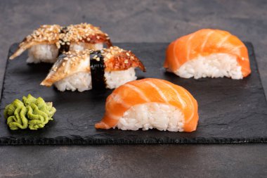 Suşi rulo ve sashimi siyah bir taş plaka.