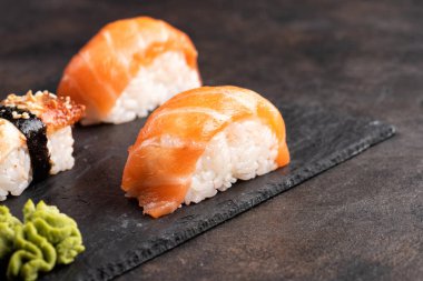 Suşi rulo ve sashimi siyah bir taş plaka.