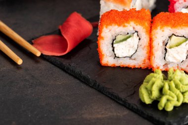 Suşi rulo ve sashimi siyah bir taş plaka.