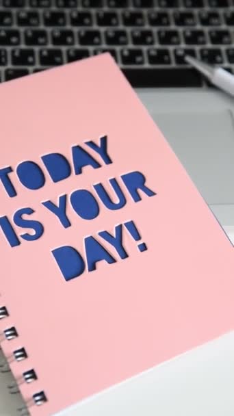 Zoom sur Table de travail avec plante verte dans un pot gris, carnet avec inscription Aujourd'hui c'est votre jour ! Ordinateur portable dans le studio du bureau. Designer freelance ou blogueur de bureau. Format vertical 