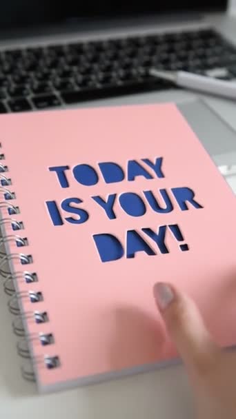 放大工作台与绿色植物在灰色的锅 女性手打开一个笔记本与题词今天是你的一天 家庭办公室工作室的笔记本电脑 自由职业者桌面 垂直格式 — 图库视频影像