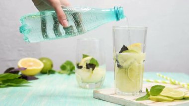Kadın el limonata veya limon, kireç ve fesleğen ile mojito kokteyl ile bardağa soda döken. Ahşap nane rengi masada buz ile soğuk serinletici içecek veya içecek. Metniniz için alan kopyalama