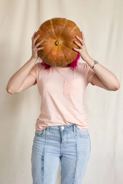 Mujer en jeans azules y camiseta rosa sosteniendo una calabaza grande —  Fotos de Stock