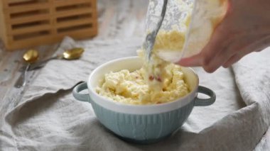 Ahşap masa üzerinde tatlı köy peynirtatlı kase. Kadın el karıştırma ve çatal ile karıştırma