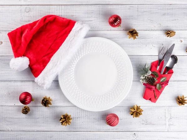 Christmas table setting with an empty plate and red Santa hat — Stock Photo, Image