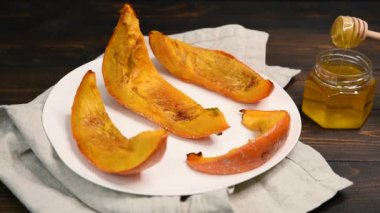 Beyaz bir tabakta kavrulmuş tatlı kabak dilimleri. Dişi el bir bal dipper tutan ve bir bal kapsayan. Sağlıklı vejetaryen, vegan gıda