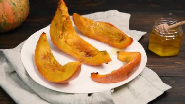 Beyaz bir tabakta kavrulmuş tatlı kabak dilimleri. Dişi el bir bal dipper tutan ve bir bal kapsayan. Sağlıklı vejetaryen, vegan gıda