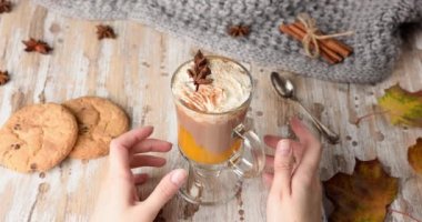 Balkabağı baharatlı latte içen kadın. Ahşap bir arka plan üzerinde üstüne krem şanti ile Tatlı çikolata sıcak içecek. 4k yavaş çekim