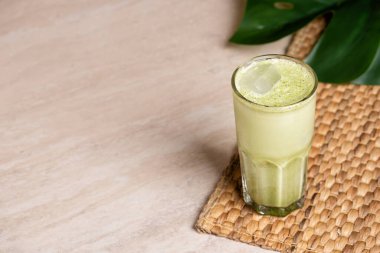 Hindistan cevizi sütlü ve mermer kaplama beyaz çikolatalı bir bardak matcha latte. Tropik canavar yaprağı.