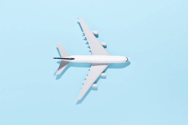 Açık mavi renkli kağıttan arka planda model uçak. Düz konum, üst görünüm ve metin için boşluk kopyala