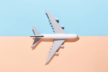 Açık mavi ve turuncu renkli kağıttan arka planda model uçak. Düz konum, üst görünüm ve metin için boşluk kopyala