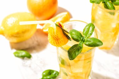 Limonlu limonata ya da mojito kokteyli, limon, portakal ve fesleğen. Mermer kesme tahtasındaki buzlu soğuk içecek ya da içecek.