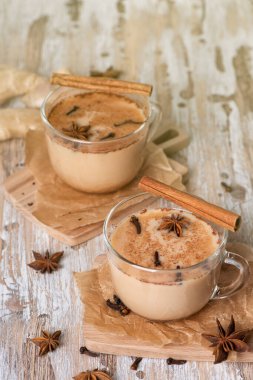 Hafif ahşap arka planda geleneksel Hint masala çayı bardakları. Siyah çay, zencefil, tarçın, kakule, anason yıldızları.