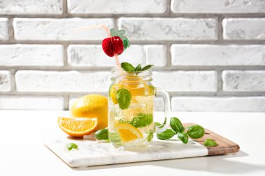Limonlu limonata ya da mojito kokteyli, limon, portakal ve fesleğen. Mermer kesme tahtasındaki buzlu soğuk içecek ya da içecek.